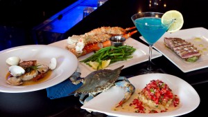 A live blue crab crawls up to say hello to a crabcake of his fallen brothers, surrounded by pan-seared red snapper, Alaskan king crab, jumbo snow crab claws, and an Electric Blue Martini. Tony Robles
