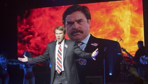 Will Ferrell poses in front of a negative ad aimed at Zach Galifianakis in "The Campaign."