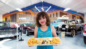 The owner’s daughter shows off a new classic, the ’75 Olds: two house-made blue cheese biscuits stuffed with beef tenderloin, bearnaise sauce, and more blue cheese. Photo by Vishal Malhotra.