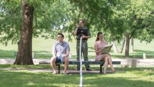 Kelsey Milbourn and Justin Lemieux (right) are separated by bureaucracy in the form of Matthew Minor in Amphibian Stage Productions’ Crossing the Line.