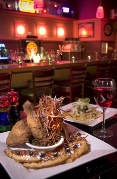 Ovation’s signature dish: chicken and waffles, with collard greens, shoestring fries, and sweet potato puree, and in the background, fried green tomatoes.