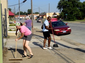 FEATURE-1 Above: Nicole Foster and Jay Johnson sweep the sidewalk during a neighborhood cleanup on Race Street. Lisa Maria Garza