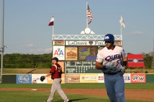 The scoreboard clock doubles as a stand for the American flag, but its face is bleached, faded, and without hands.