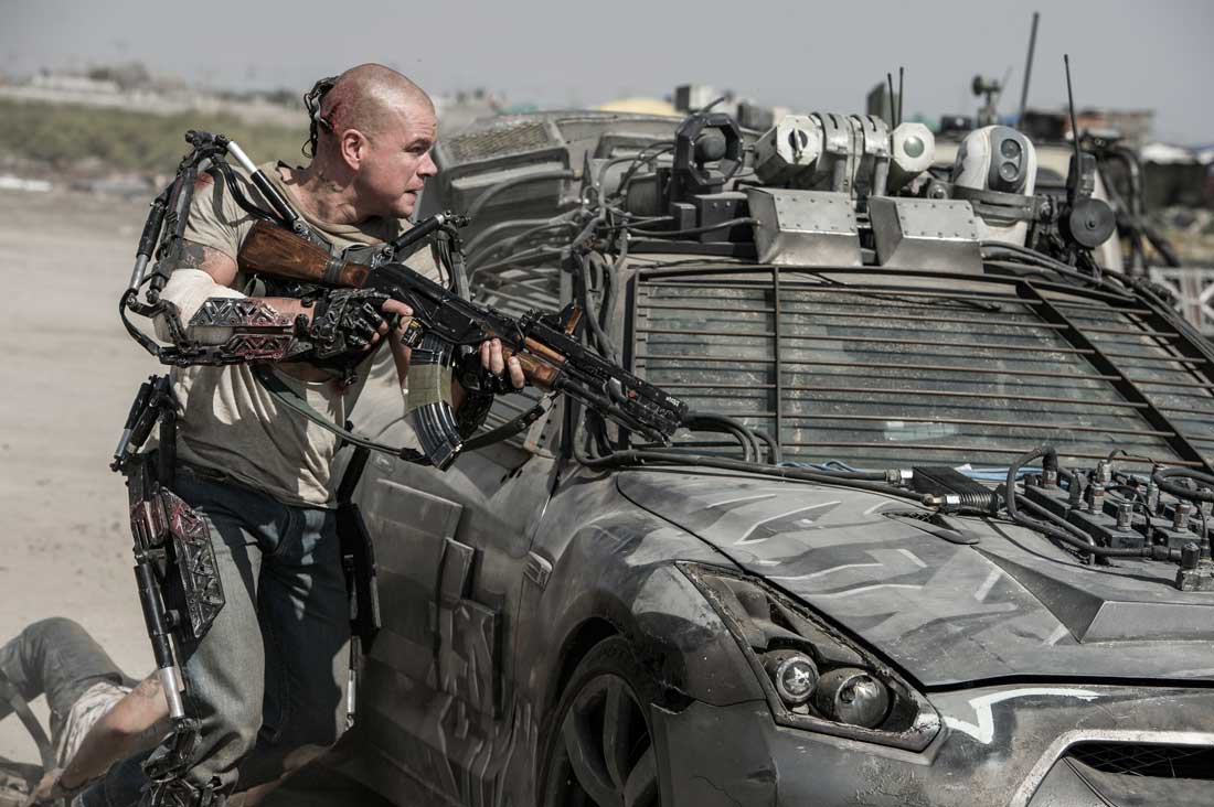 Matt Damon takes cover behind a military vehicle (and his metal exoskeleton) in Elysium.