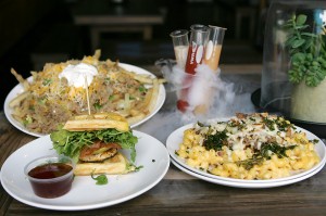 Accompanying the chicken-bacon-apple waffle sandwich are Bunsen’s Baked Brisket Mac (right) and loaded Potassium fries.