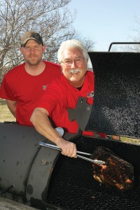 Owner Mike Fisher (right) and assistant pit master Donald Phillips pull some brisket off the fire. Lee Chastain