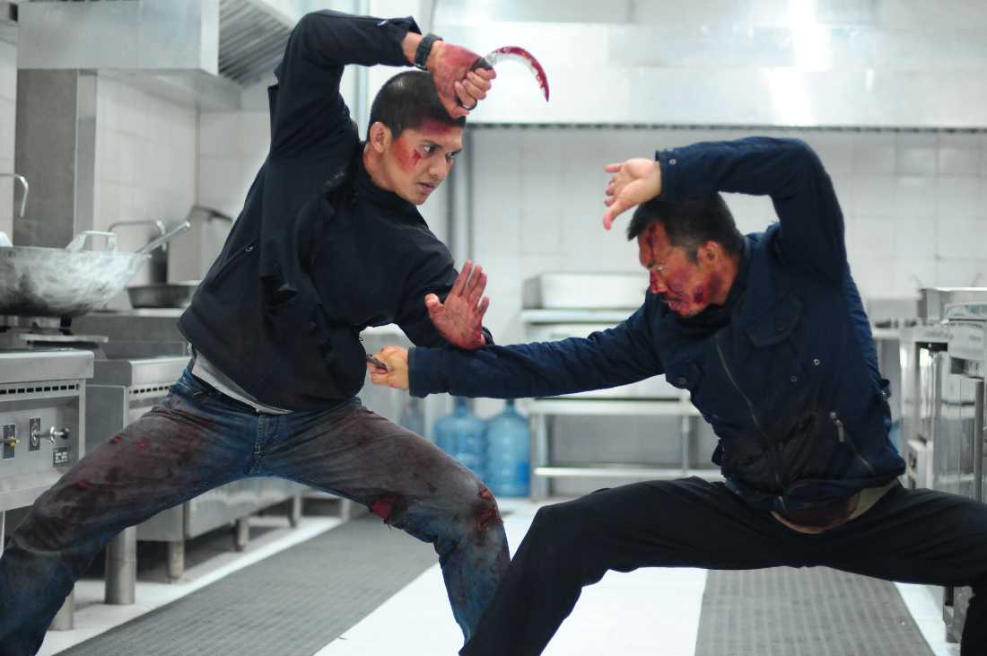 Iko Uwais and Cecep Arif Rahman go at each other with curved blades in a restaurant kitchen in The Raid 2.