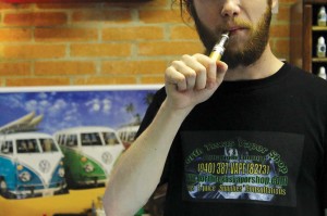 North Texas Vapor Shop employee Chase Fowler takes a drag on his e-cig behind the counter. Melissa Wylie