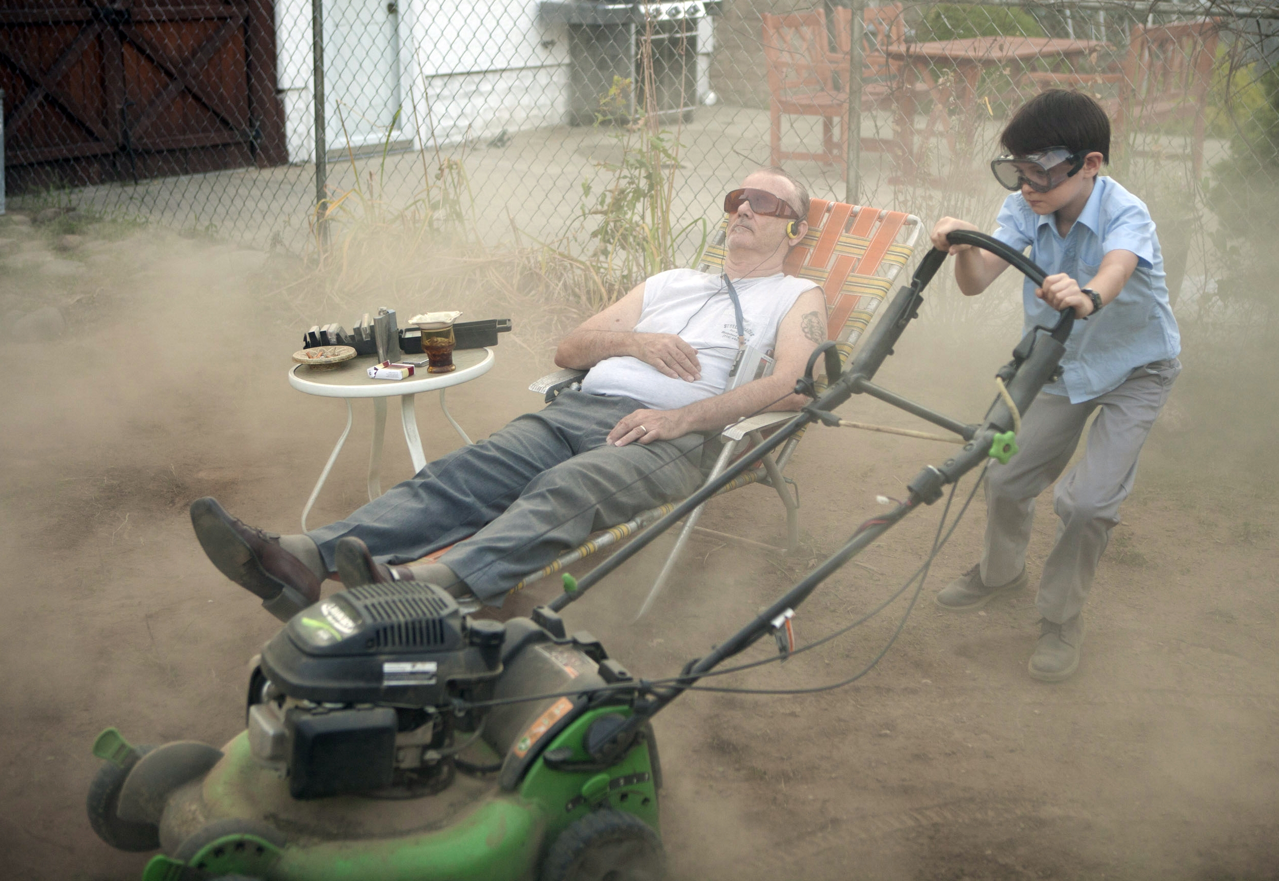 Bill Murray relaxes while Jaeden Lieberher mows his lawn in St. Vincent.