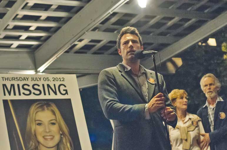 Ben Affleck stands next to Rosamund Pike’s picture as he asks for the public’s help in Gone Girl.