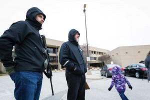 Open Carry Tarrant County members wait with weapons in Arlington, as a child plays nearby.