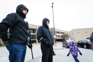 Feature-3 Open Carry Tarrant County members wait with weapons in Arlington, as a child plays nearby.
