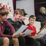Students (left to right) Will Gassner, Kjell Pedersen, Levi Patton, McCormick Van Vleet, Maverick Knight, and Kaylee Yates find some humor in their scripts at rehearsal.