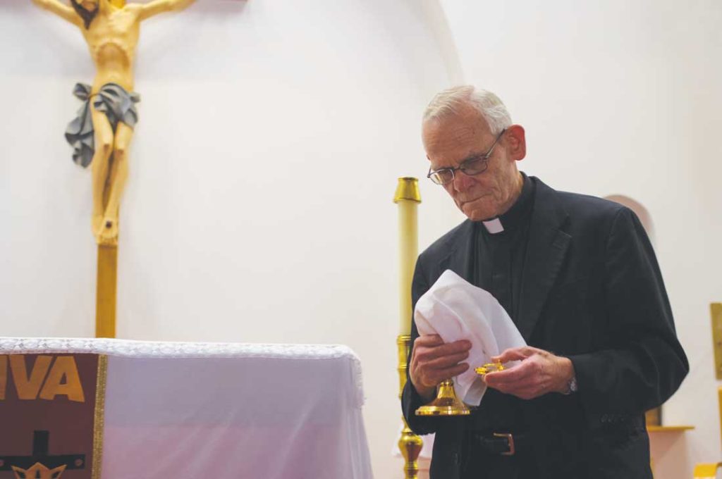 Father Bob Strittmatter removes the Eucharist from the sanctuary of San Mateo after the final Mass, effectively “killing the church,” as one congregation member cried out. Photo by Matthew Brown.