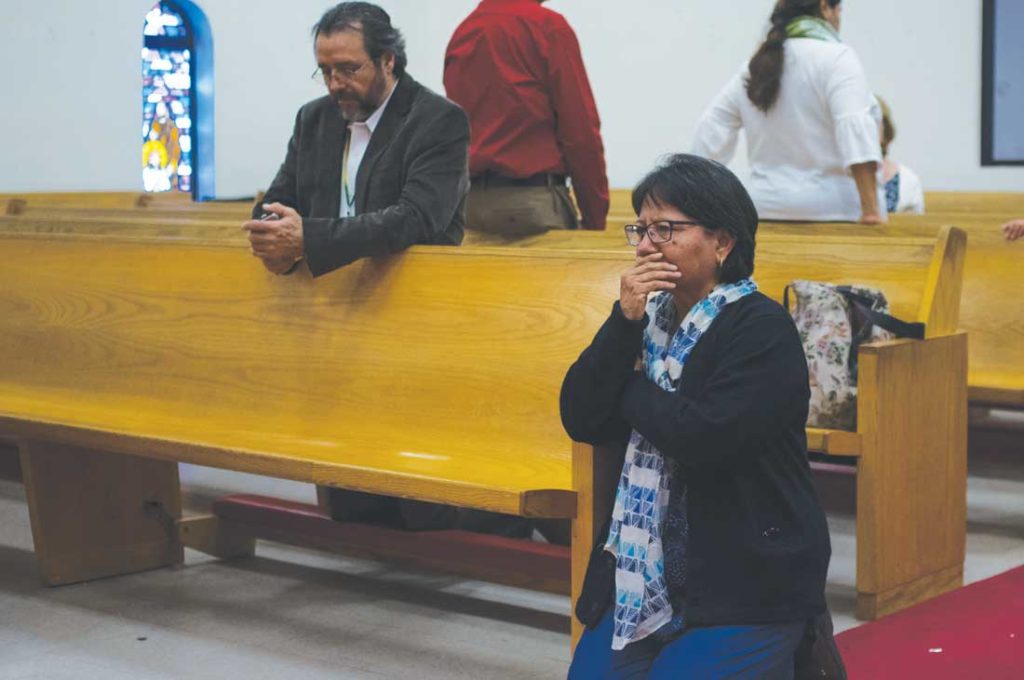 Parishioners of San Mateo cry and pray for their mission at the end of its final service. Photo by Mattew Brown.