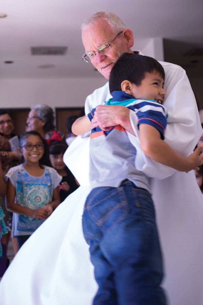 Father Bob Strittmatter twirls a young member of his congregation at the end of Mass. Photo by Matthew Brown.