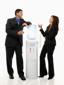 Vietnamese businesswoman and Indian businessman conversing at water cooler.