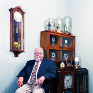 Bill Edwards sits surrounded by his unusually eclectic collection of very early 19th and 20th century windup, electrical, and wooden movement clocks. Photo by Chirag Sainju.