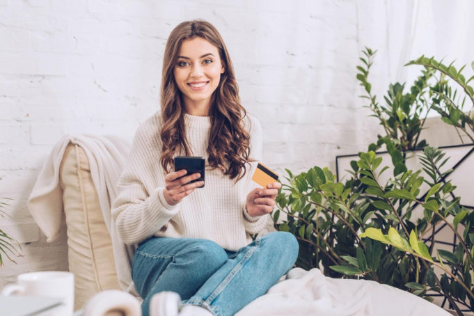 A young woman holding a calculator and a credit card.