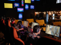 What Makes a Great Esports Tournament? Group of gamers wearing headsets playing multiplayer PC games in a neon-lit esports arena.
