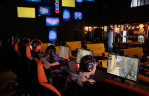 What Makes a Great Esports Tournament? Group of gamers wearing headsets playing multiplayer PC games in a neon-lit esports arena.